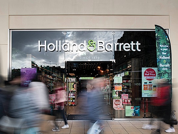 exterior of a Holland & barrett store, with blurred shoppers walking past